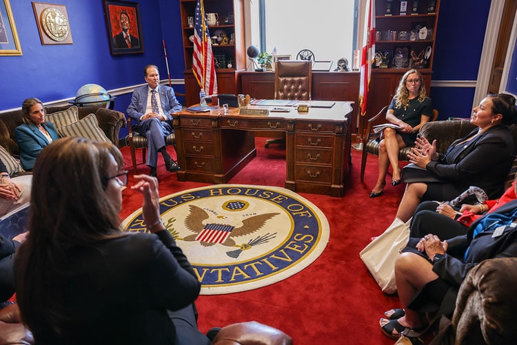Caregivers and officials in a formal meeting in the White House office.