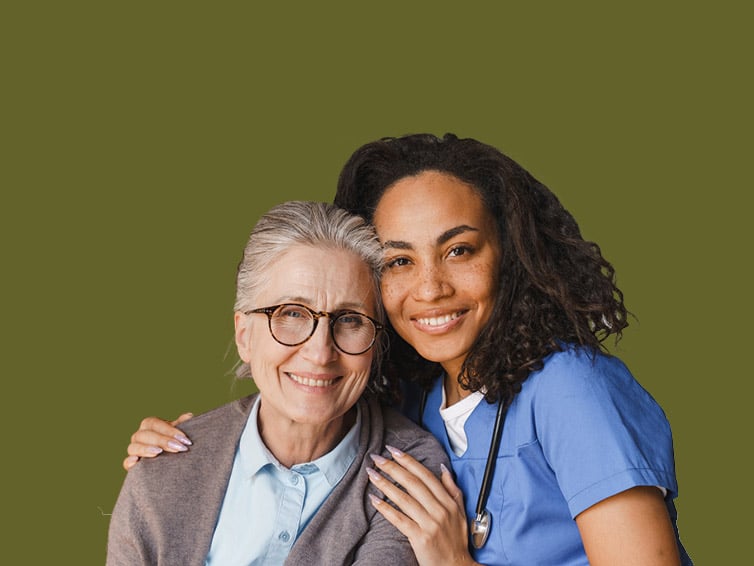 Two women, one elderly and one young caregiver, smiling together.