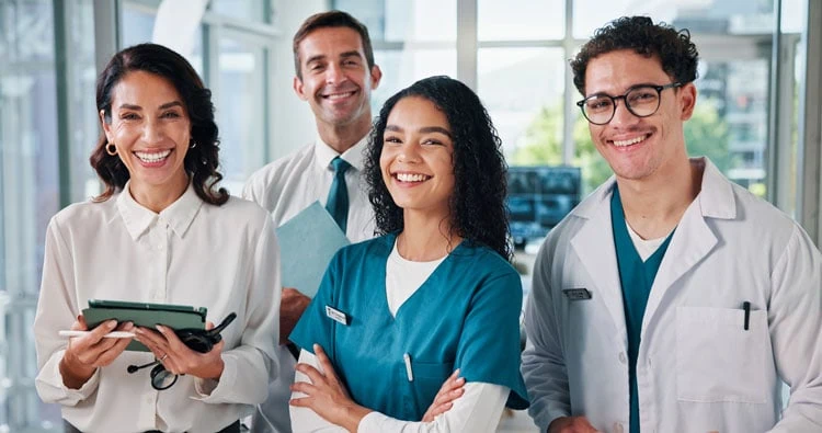 Healthcare team of diverse caregivers and professionals smiling in a medical setting.