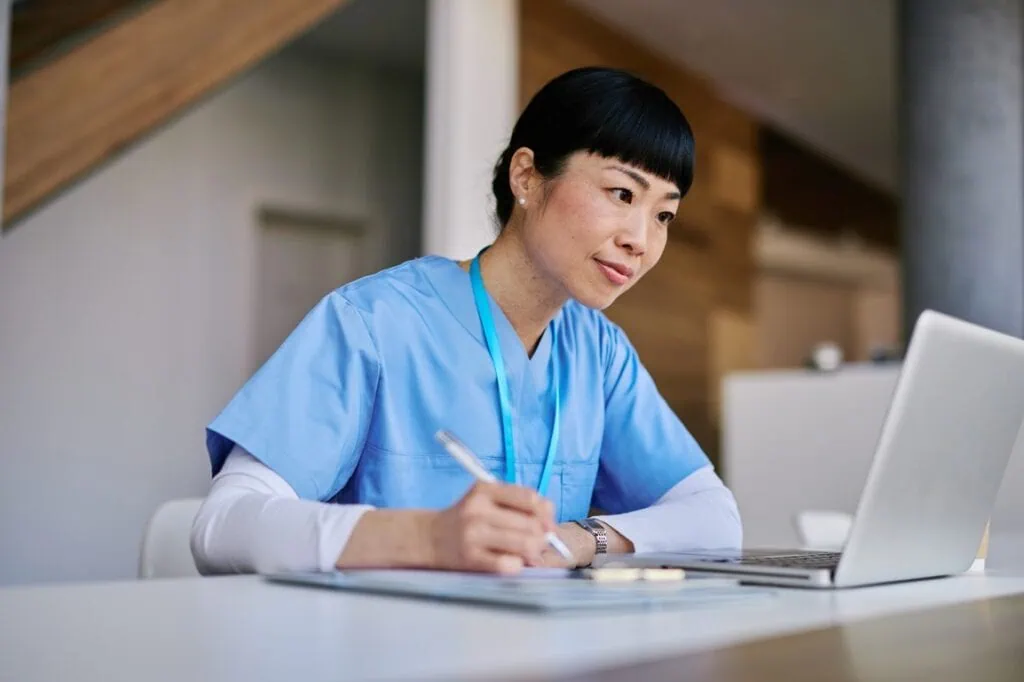 Caregiver taking notes during online learning session on caregiving.