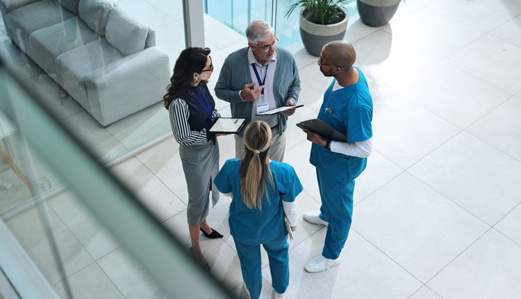 Healthcare professionals and caregiver discuss patient care in a hospital setting.